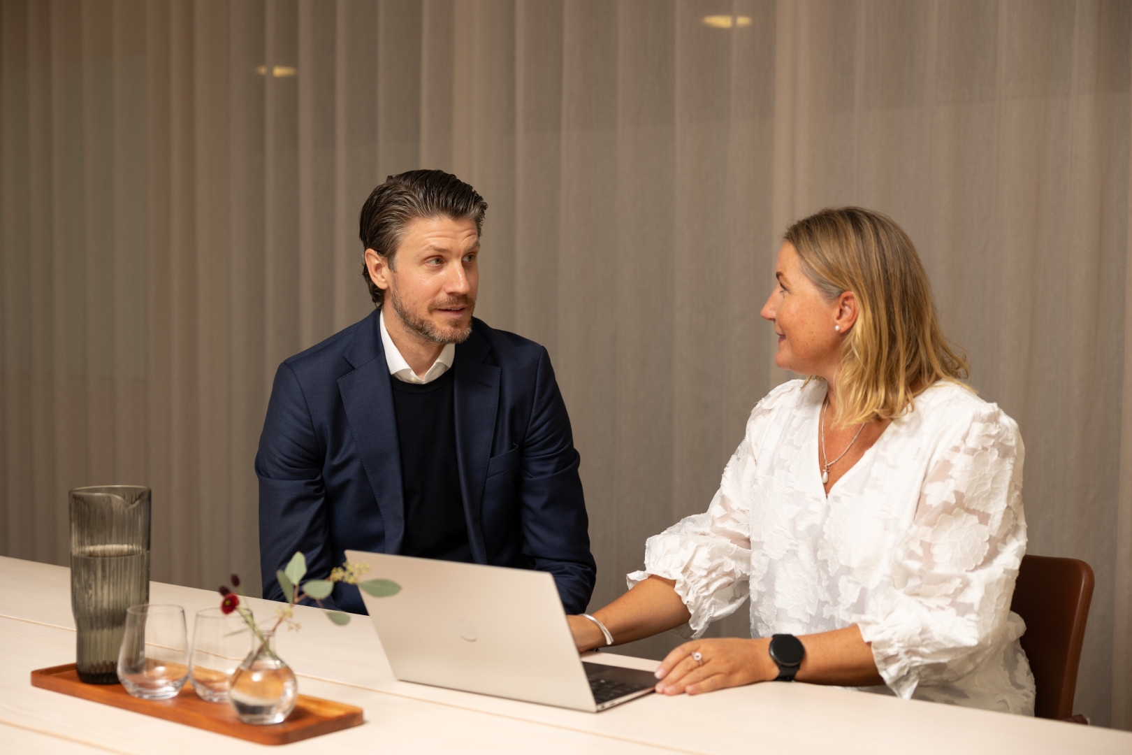 Två medarbetare från SJR pratar om konsultlösningar i ett ljust rum där engagemang och professionalism präglar samtalet.