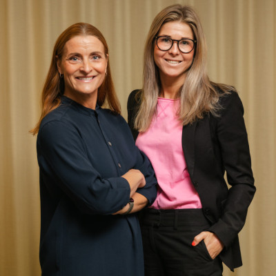 Två medarbetare från SJR står sida vid sida i professionell klädsel. Bilden signalerar både förtroende och expertis inom strategisk bemanning. Båda jobbar aktivt med Interim Management på SJR