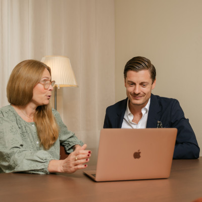 En man och en kvinna diskuterar vid en bärbar dator i ett dämpat kontor, där SJR möjliggör träffsäker kompetensmatchning genom erfarenhet, löpande dialog och moderna verktyg.