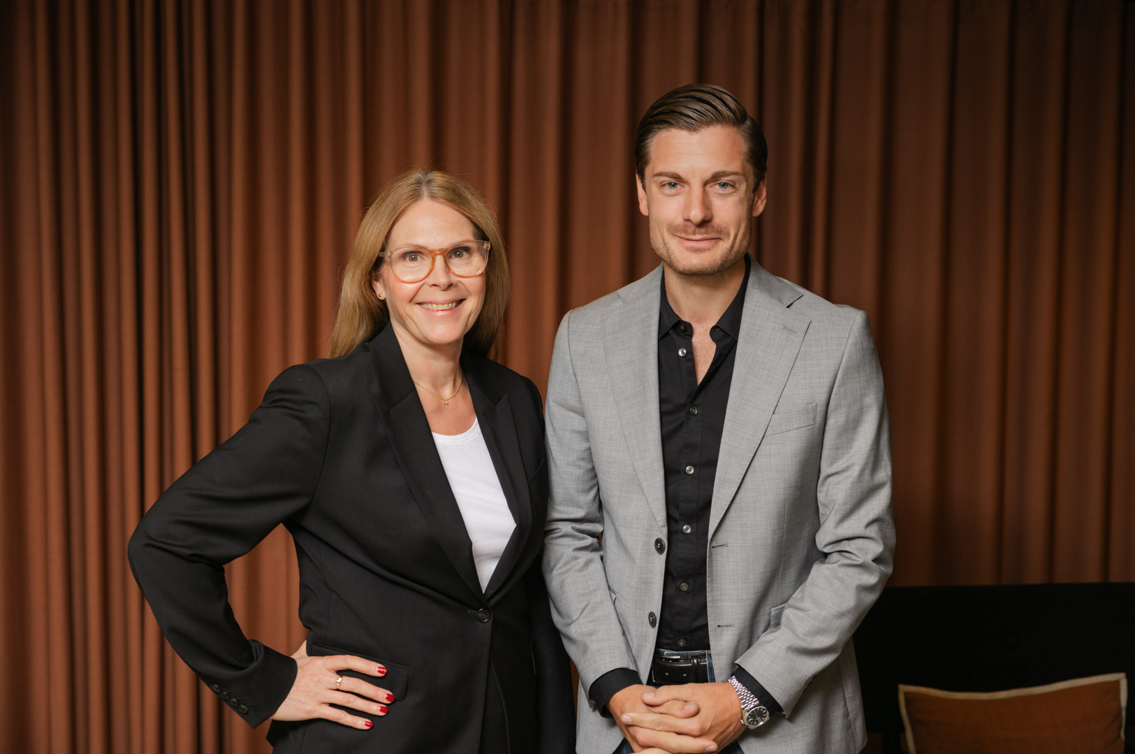 Två kollegor från SJR poserar tillsammans med självsäkerhet i en varm inomhusmiljö, redo att möta kundernas behov av hållbara rekryterings- och konsultlösningar.