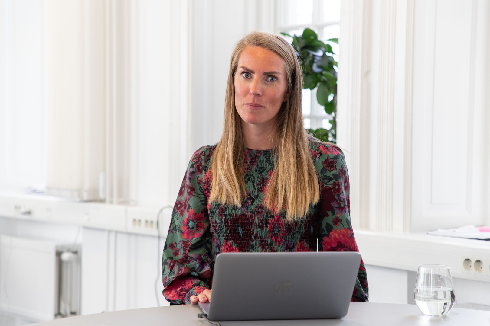 En SJR kvinnlig medarbetare i Malmö sitter i ett ljust och öppet kontorslandskap med ett välkomnande leende – redo att stötta kunder med rekrytering och konsultlösningar inom ekonomi, finans och HR.