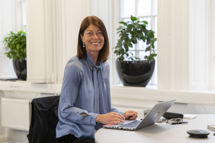 En SJR medarbetare i Malmö sitter i ett öppet kontorslandskap med ett välkomnande leende – redo att stötta kunder med rekrytering och konsultlösningar inom ekonomi, finans och HR.
