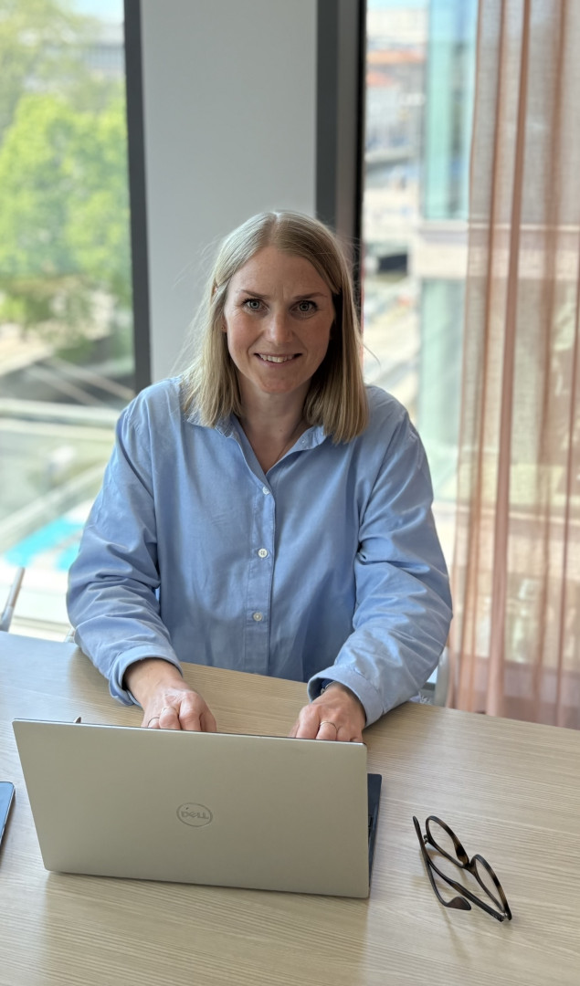 Karin Fors, konsultchef på SJR i Göteborg, sitter i ett ljust konferensrum med utsikt över centrala Göteborg och jobbar på en laptop med ett välkomnande leende.