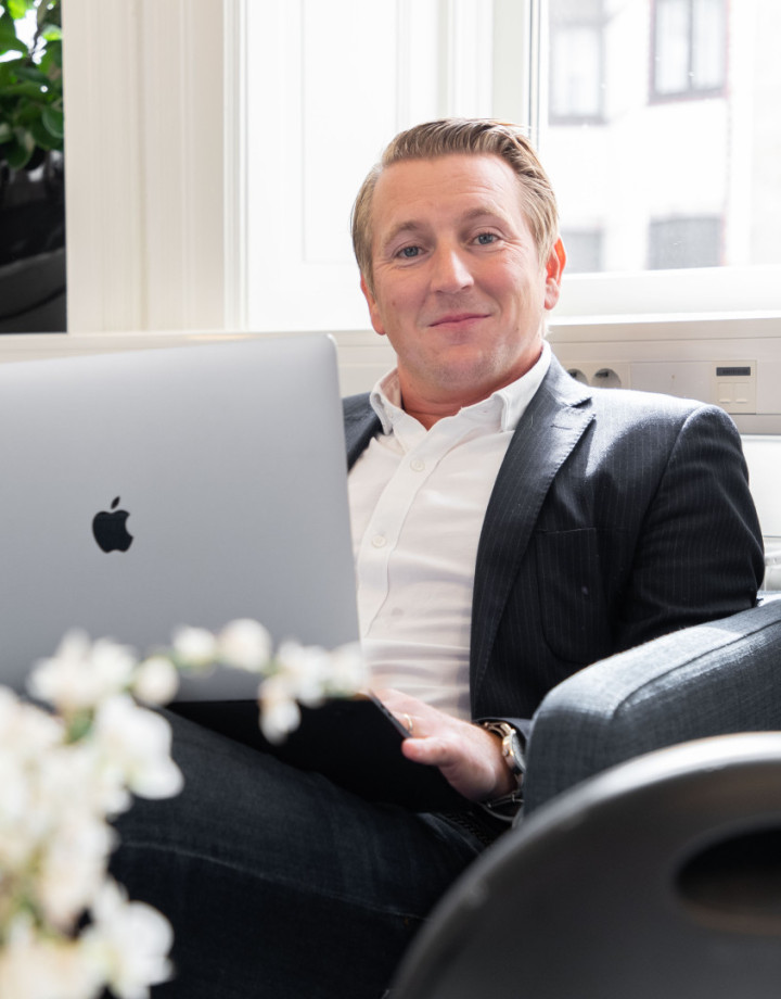 En manlig kollega från SJR som sitter med sin laptop, klädd i kavaj och utstrålar professionalism och förtroendefulla relationer.