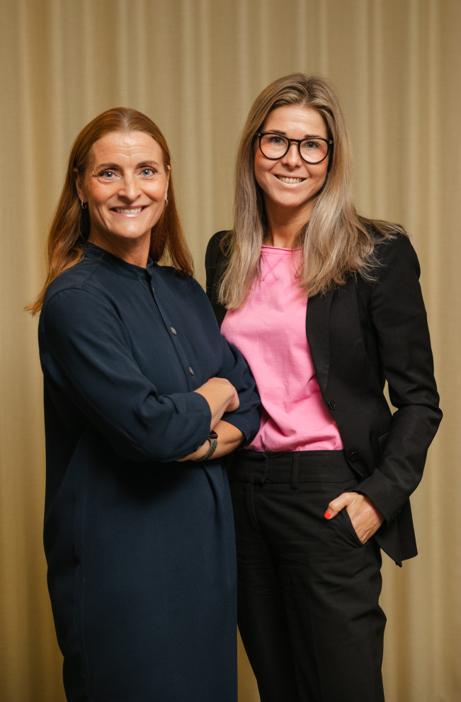 Två kvinnliga kollegor från SJR som står tillsammans och utstrålar professionalism och förtroendefulla relationer.